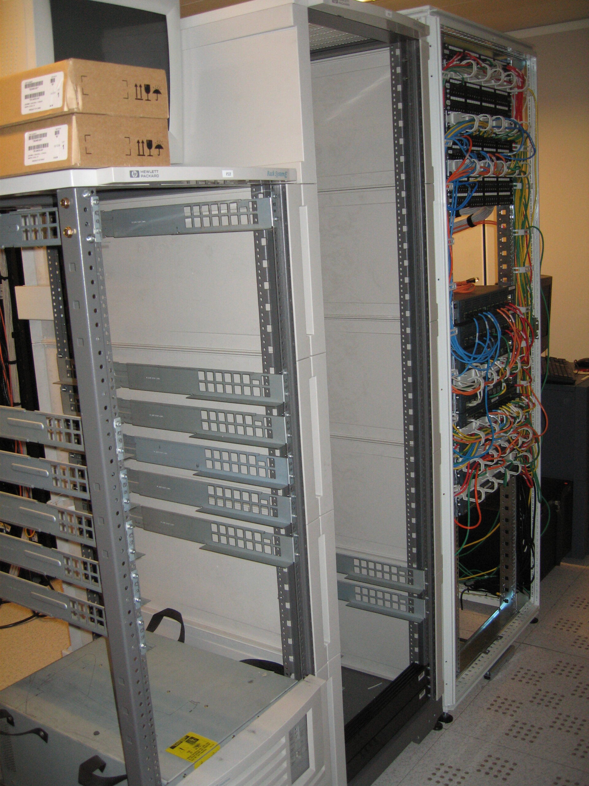 Equipment racks containing servers beside an empty rack.